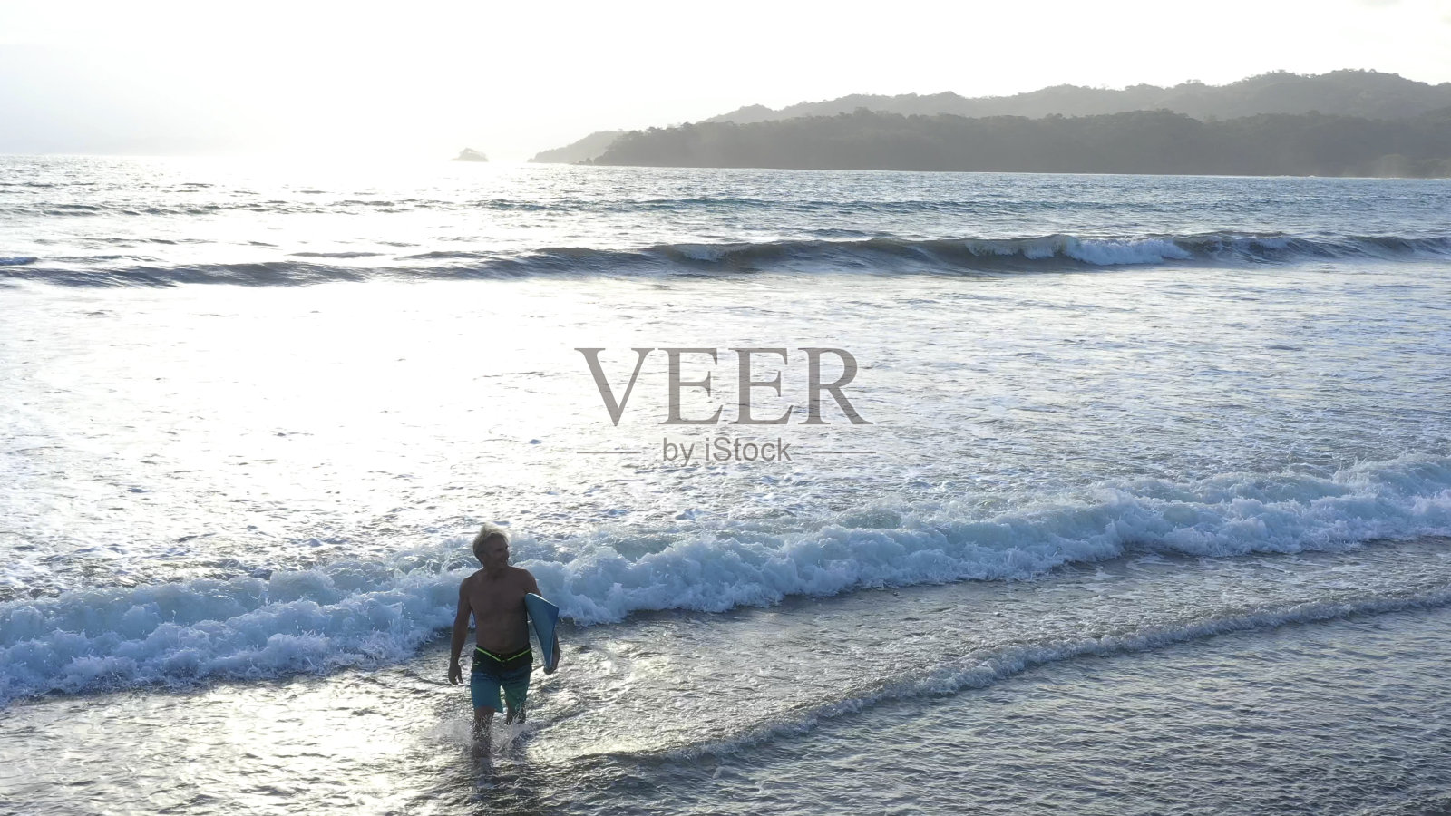 日出时分，一名男子带着冲浪板奔向太平洋照片摄影图片