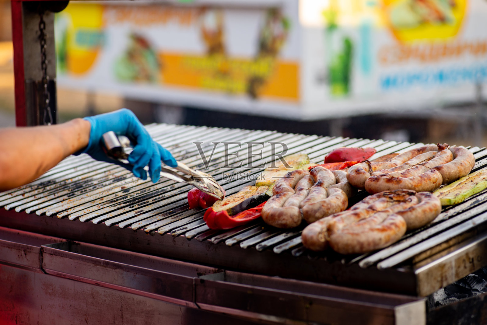 厨师把烤好的香肠和蔬菜翻过来。街头食品。烧烤野餐照片摄影图片