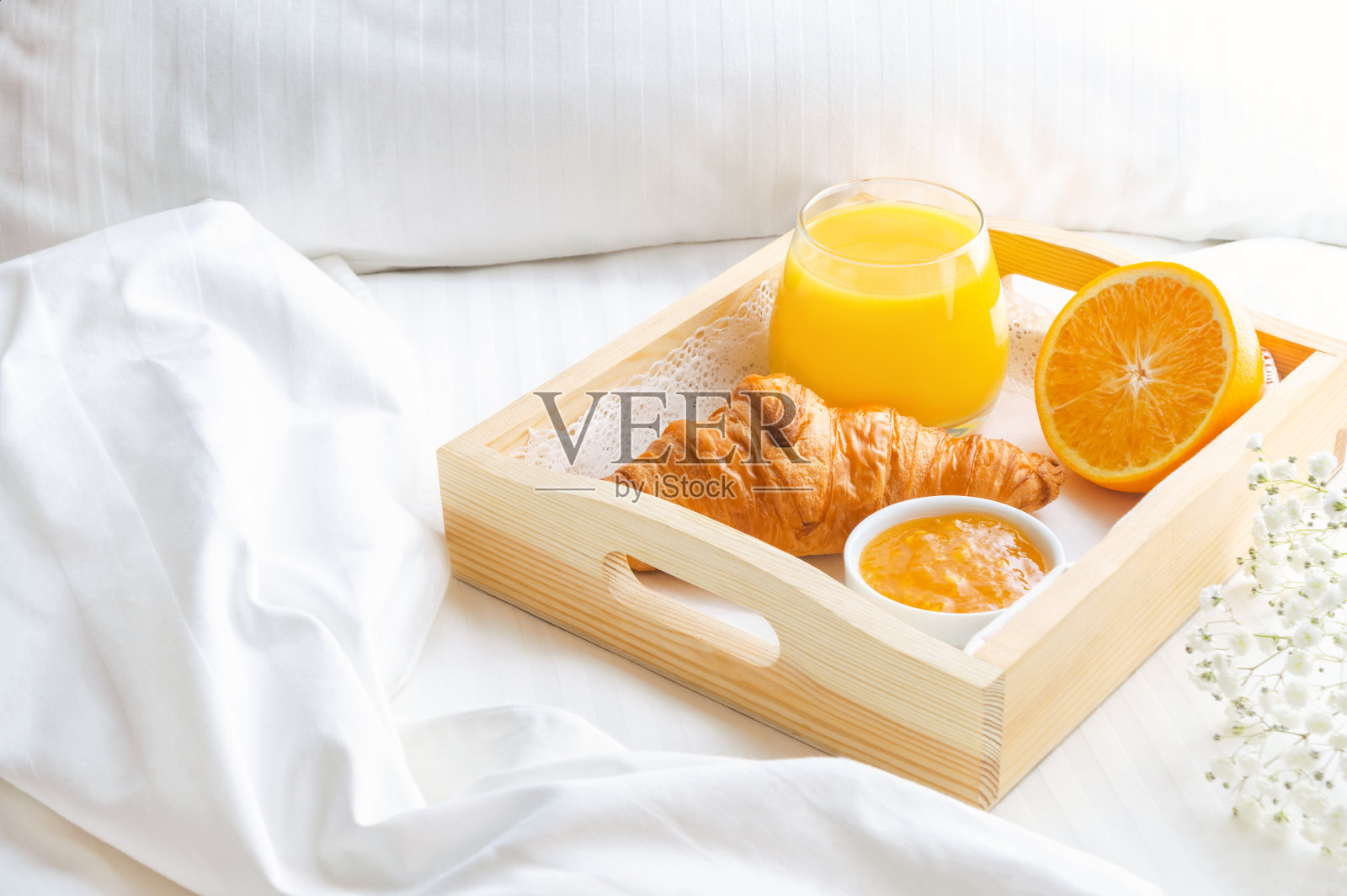 早餐在床上，橙汁放在木托盘上。照片摄影图片