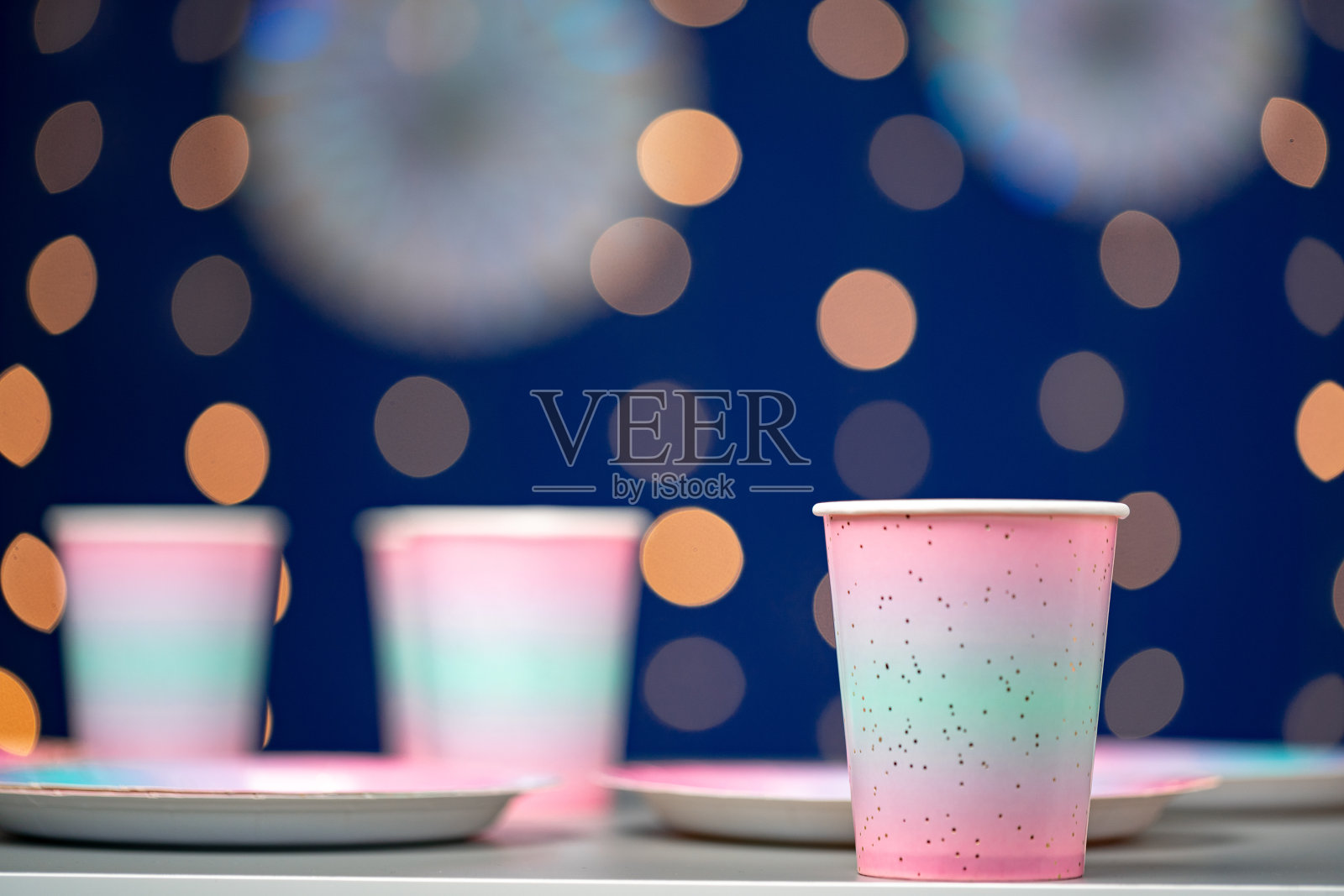 蓝色散景背景上的粉色一次性杯子照片摄影图片
