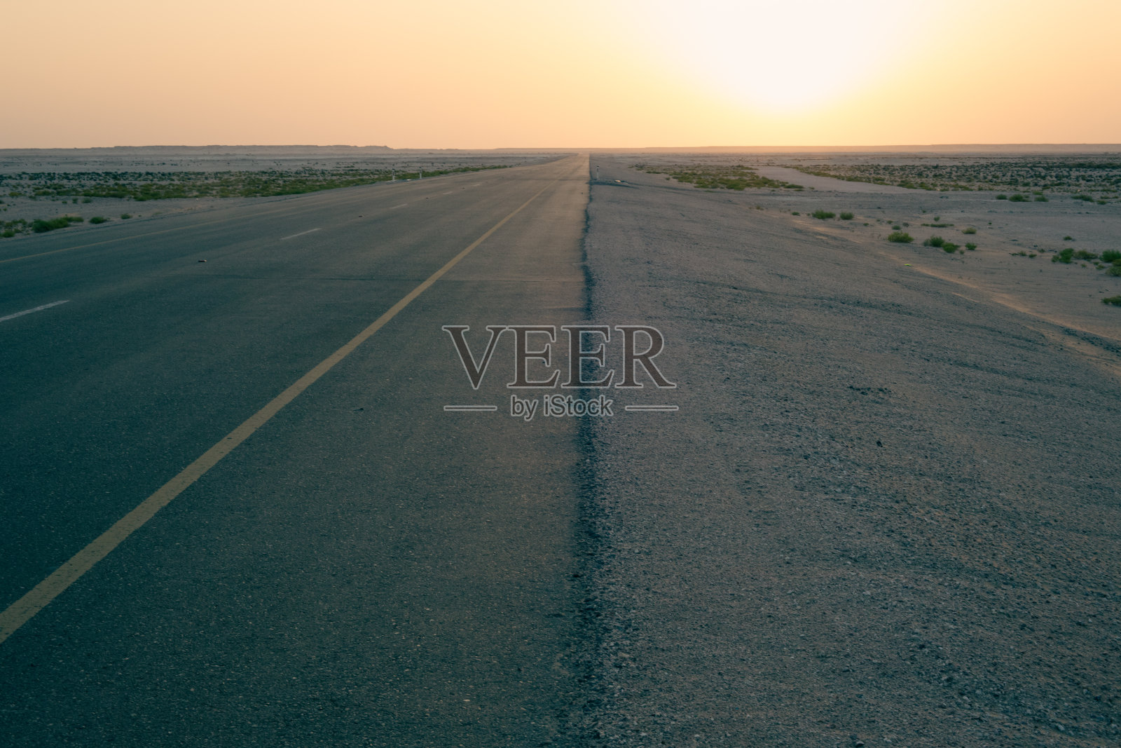 日出时分空旷单车道穿过平坦沙漠照片摄影图片