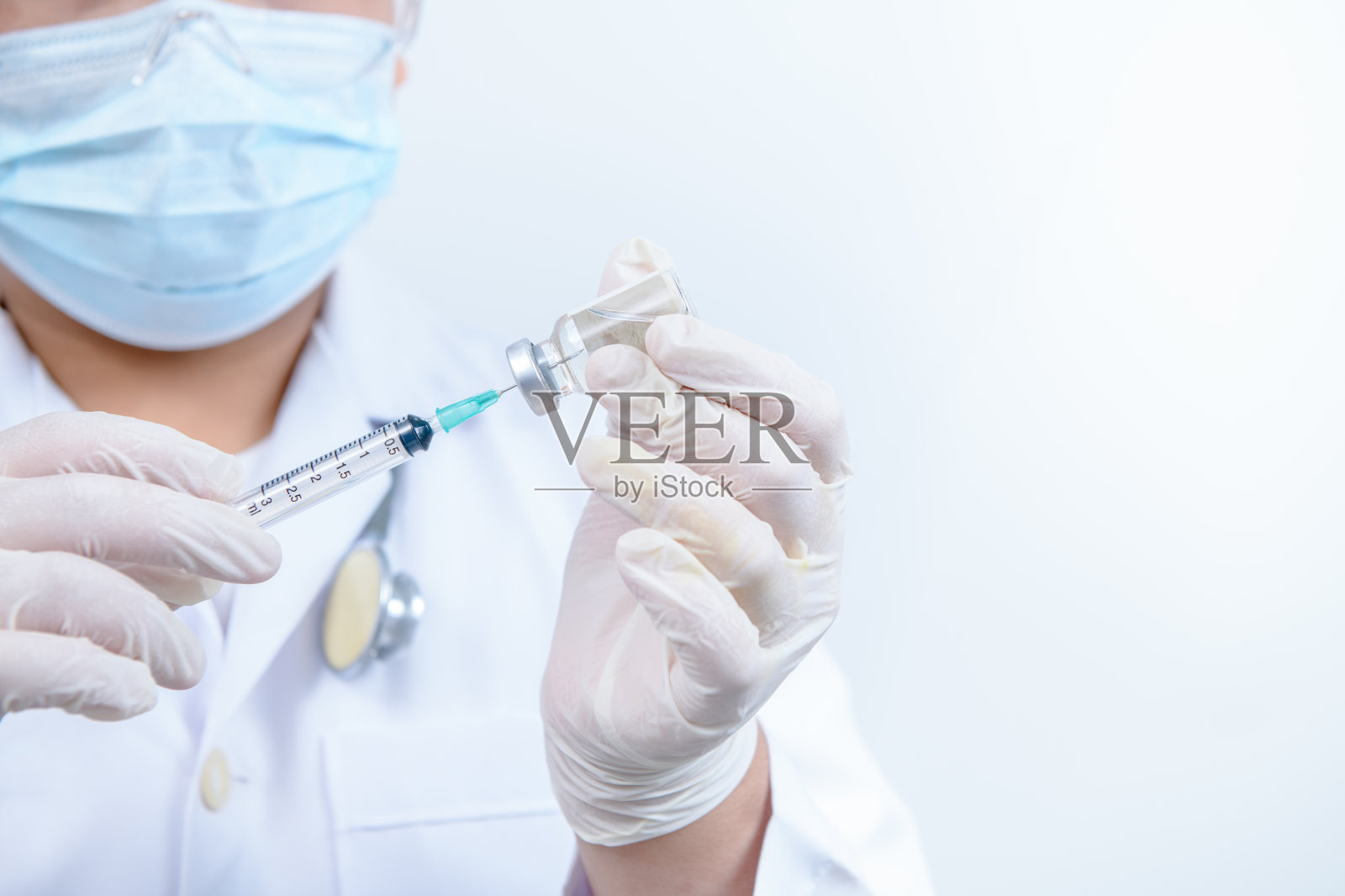 医生或科学家穿着长袍，拿着装有液体疫苗的注射器。医学和科学概念照片摄影图片