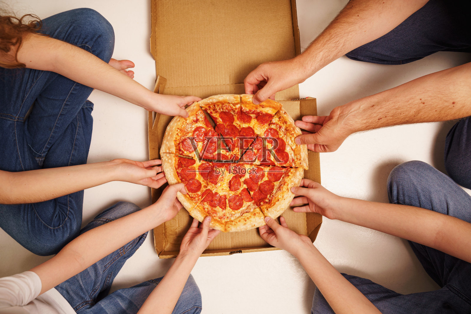 家人在吃意大利辣香肠披萨。照片摄影图片