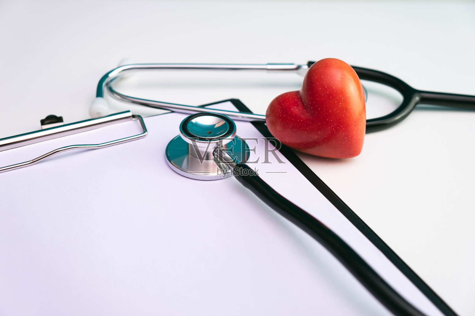 写字板、听诊器和白色背景上的石红心照片摄影图片