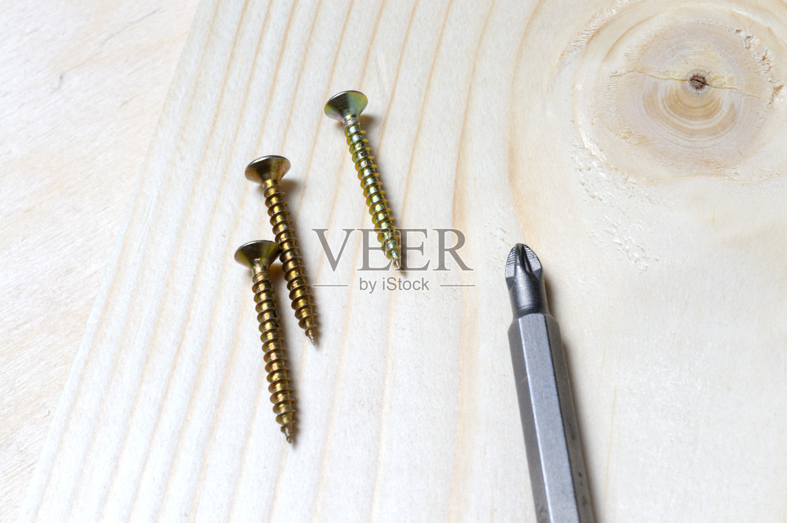 一块木头上放着一个螺丝刀和一些自攻螺钉。特写镜头。照片摄影图片