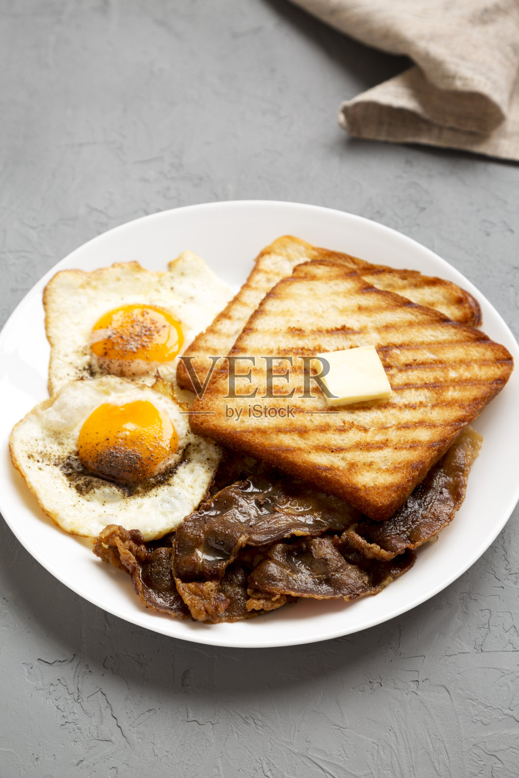 自制健康阳光鸡蛋早餐在一个白色的盘子上，在一个灰色的表面，侧面。照片摄影图片