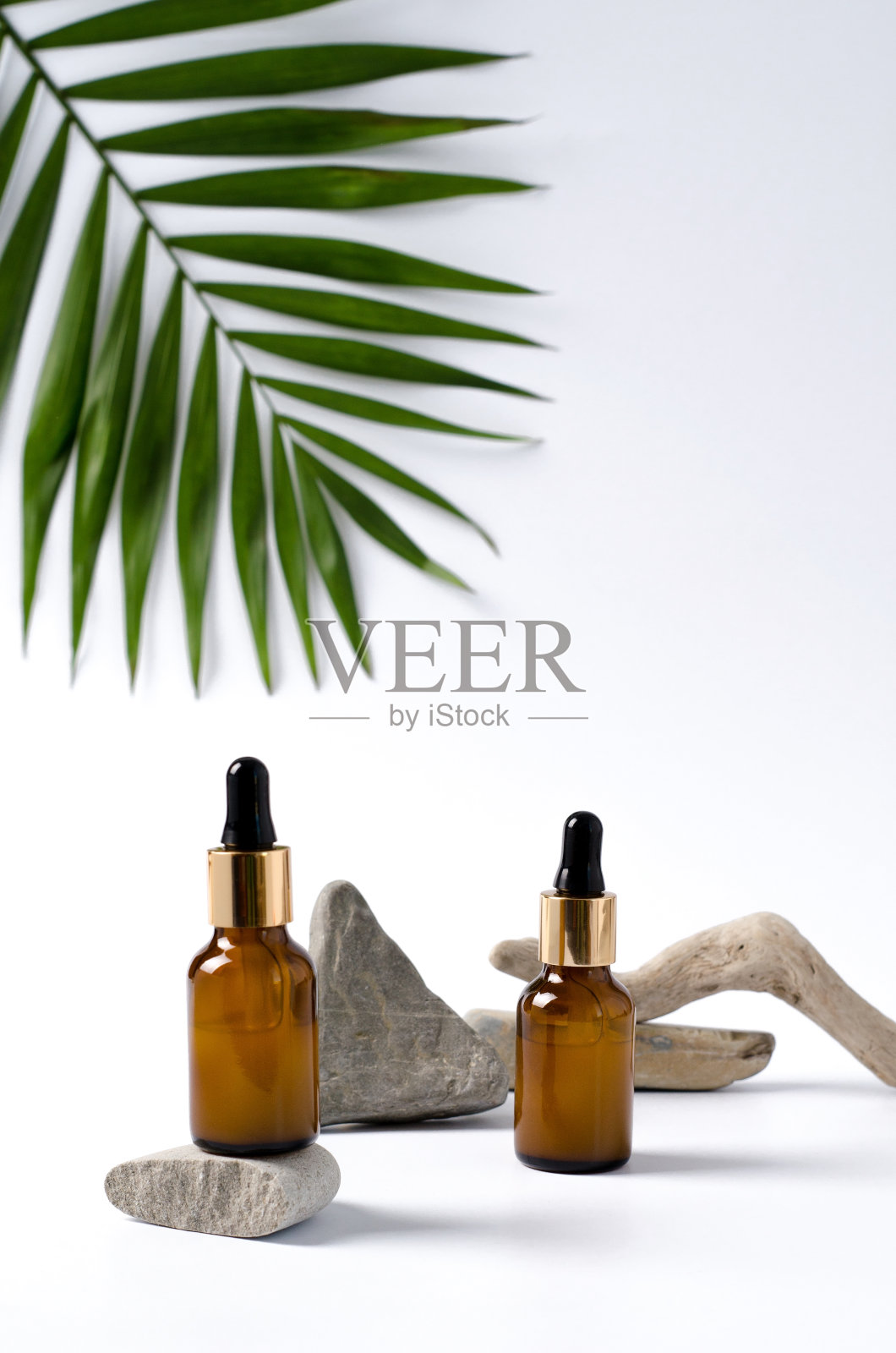 血清和移液管放在深色玻璃瓶里。用天然的石头和树枝构成背景。照片摄影图片