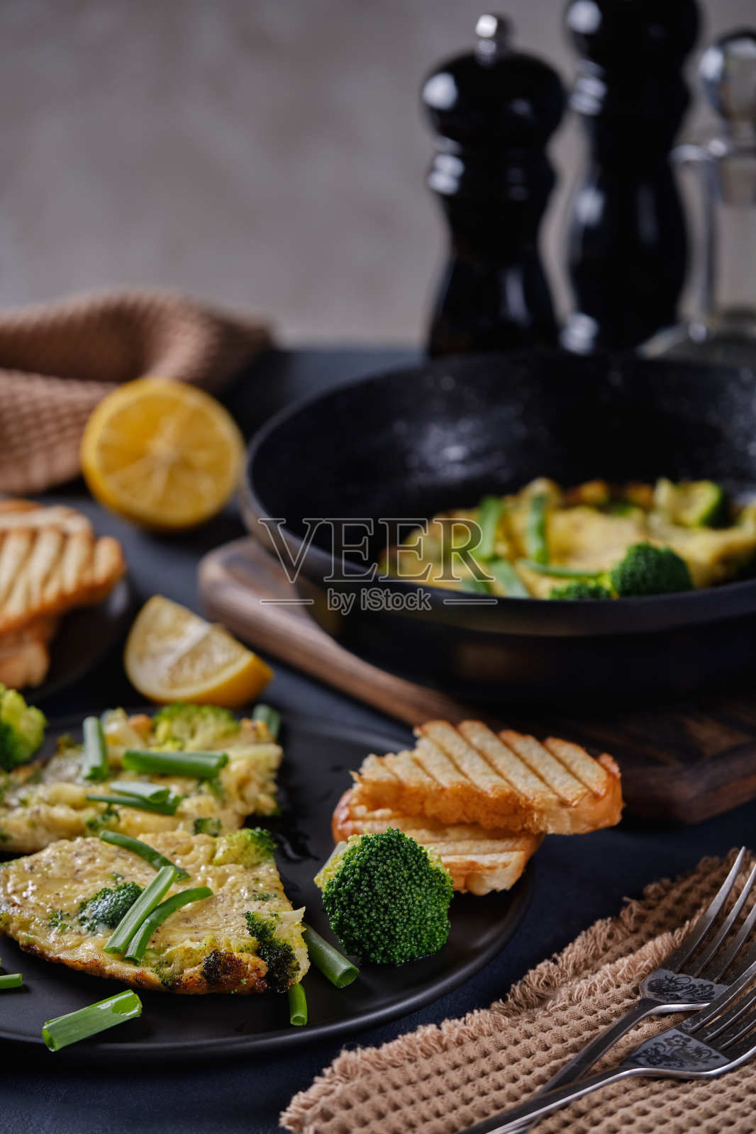 用黑色的盘子和平底锅在黑色的背景上煎，配上西兰花和葱照片摄影图片