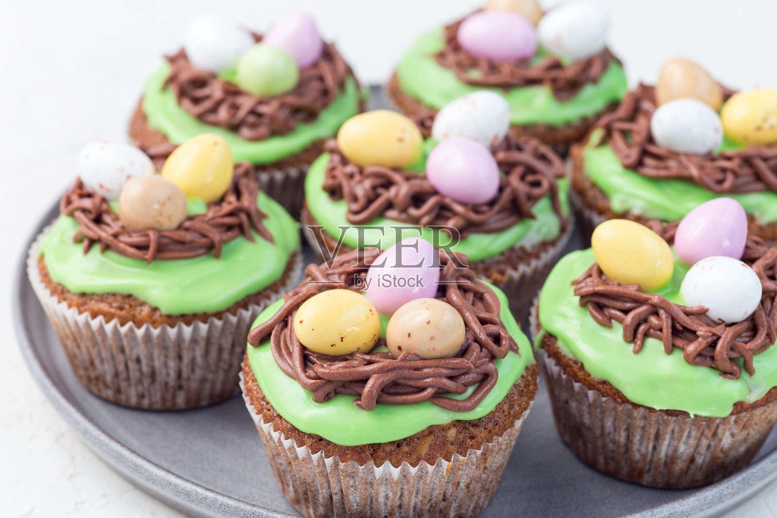 有奶油芝士糖霜和复活节巧克力蛋的胡萝卜纸杯蛋糕，横放在灰色的盘子里照片摄影图片