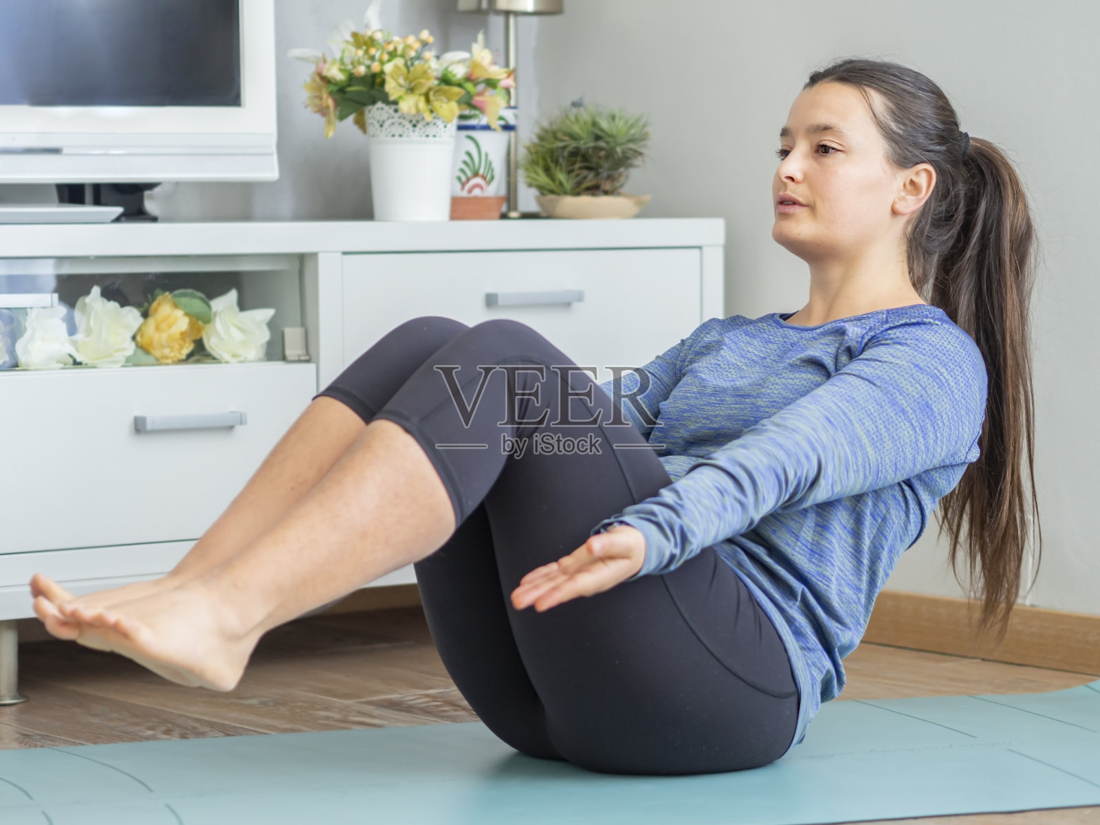 年轻女子在家锻炼腹肌。照片摄影图片