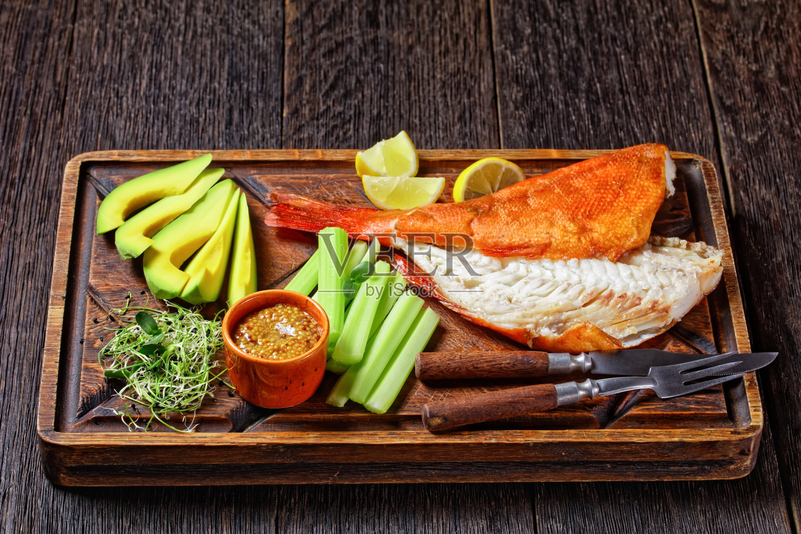 冷烟熏红鲷鱼配芹菜、柠檬角、牛油果片和微绿蔬菜，放在粗糙的木托盘上，放在一张质朴的桌子上，从上面往下看照片摄影图片