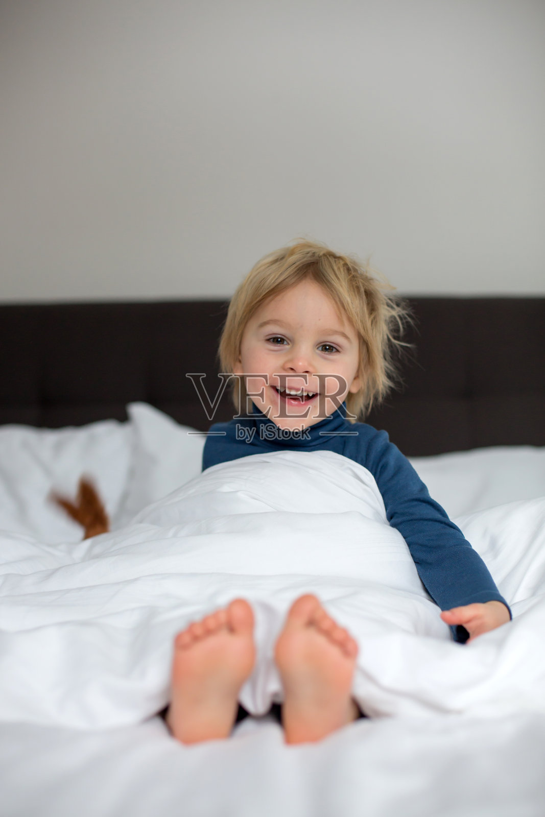 可爱的孩子，躺在床上，玩着小玩具照片摄影图片