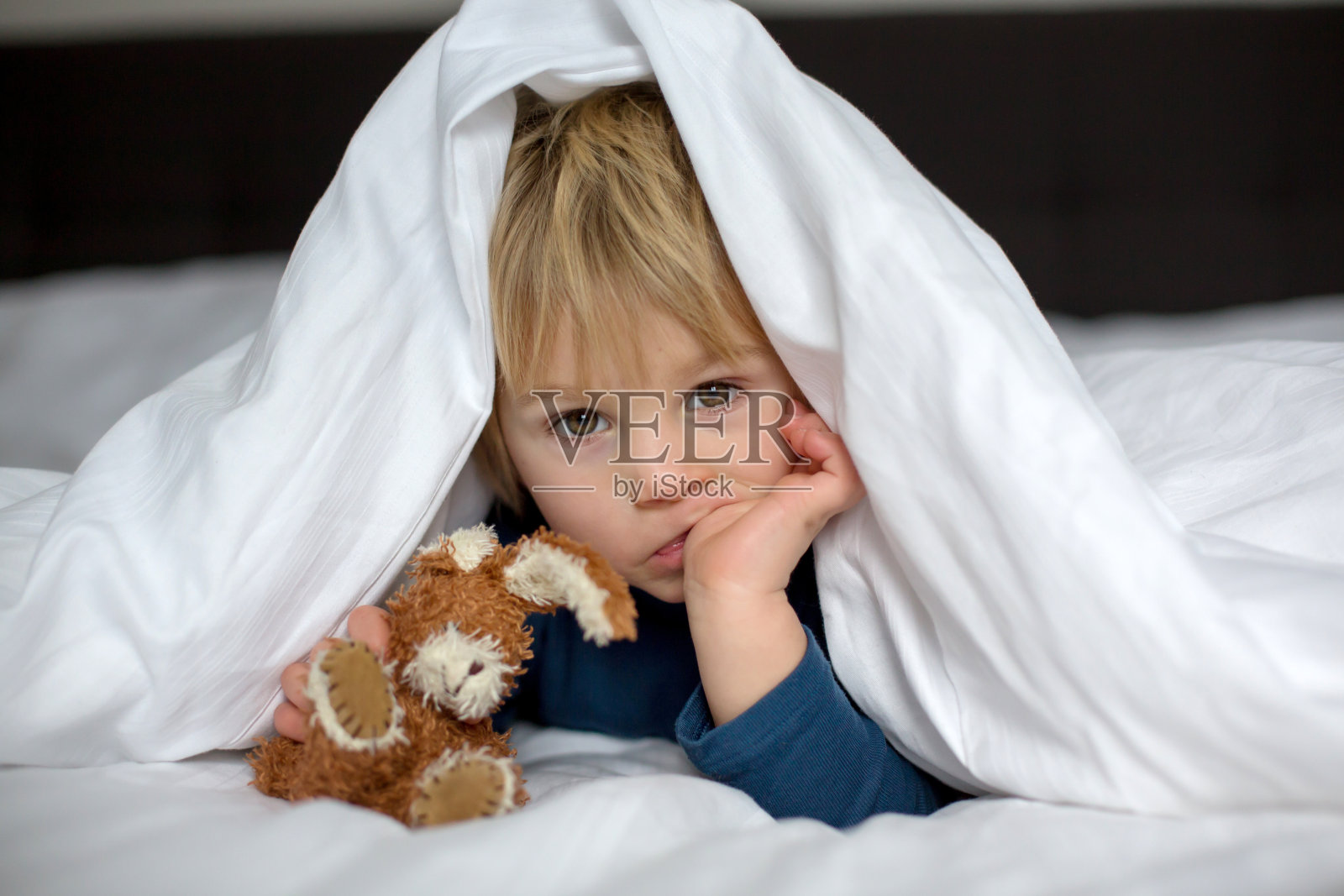 可爱的孩子，躺在床上，玩着小玩具照片摄影图片