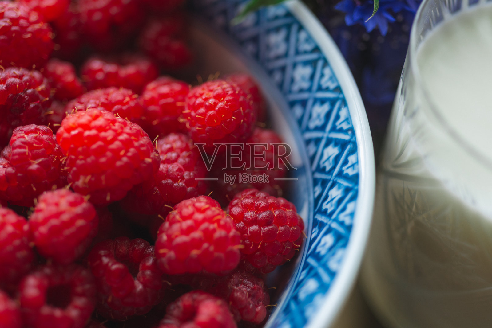 特写新鲜有机覆盆子在一个盘子和一杯牛奶照片摄影图片