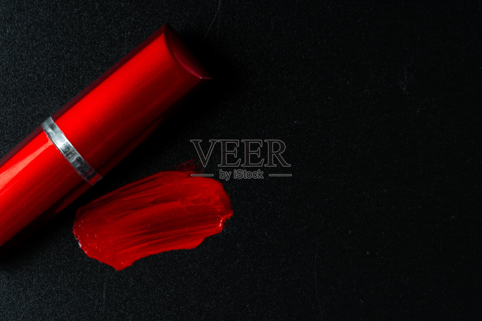 红色的口红在深色的纸背景近处照片摄影图片