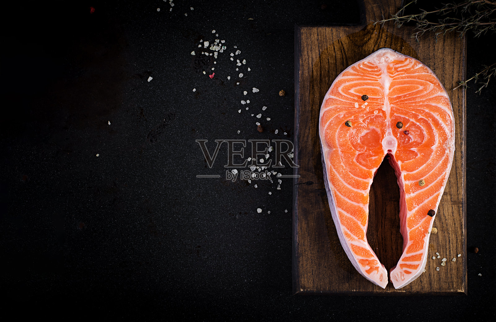 鲑鱼。生鲑鱼排鱼片与烹饪原料，香草和柠檬在黑色背景与复制空间。俯视图，上方，拷贝空间。照片摄影图片