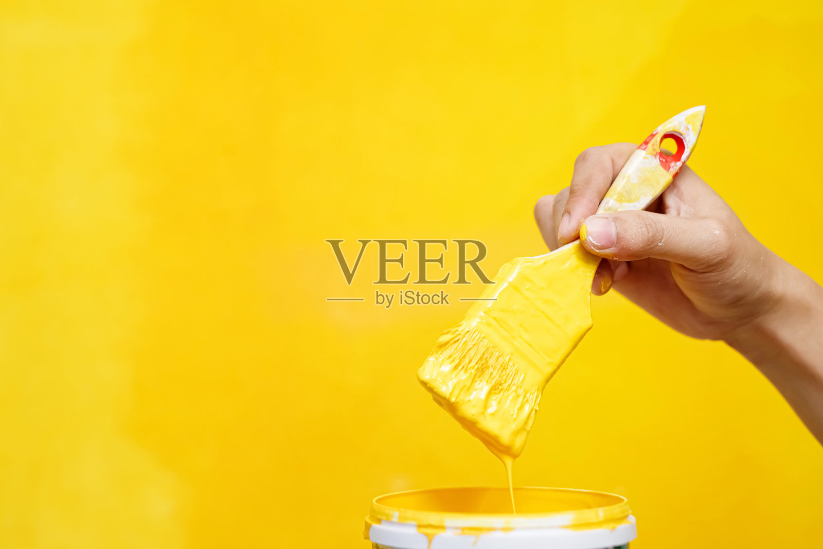 油漆工正把墙壁漆成黄色，以衬托起居室的内部。照片摄影图片