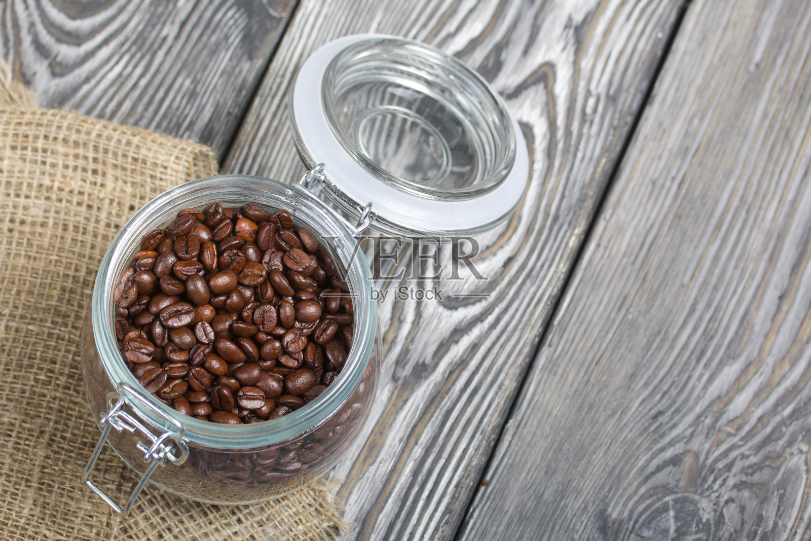 咖啡豆。倒入一个拉锁罐。站在亚麻和松木木板上。从上面射照片摄影图片