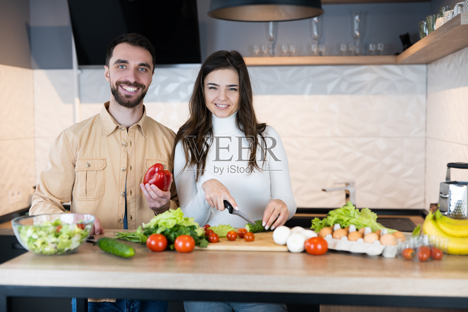 这对可爱的素食夫妇正在展示他们是多么的健康和强壮。快乐的素食主义者只使用营养和健康的食物做沙拉。照片摄影图片