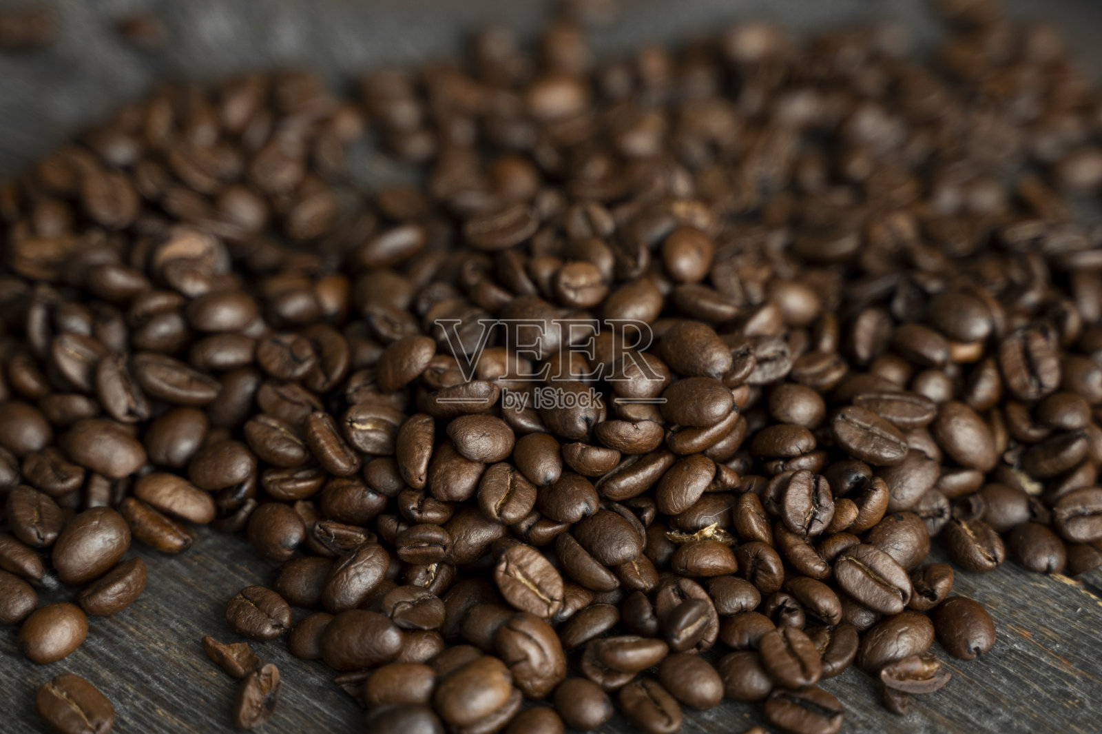 烤过的阿拉比卡咖啡豆散落在一张木桌上。新鲜的咖啡豆。照片摄影图片