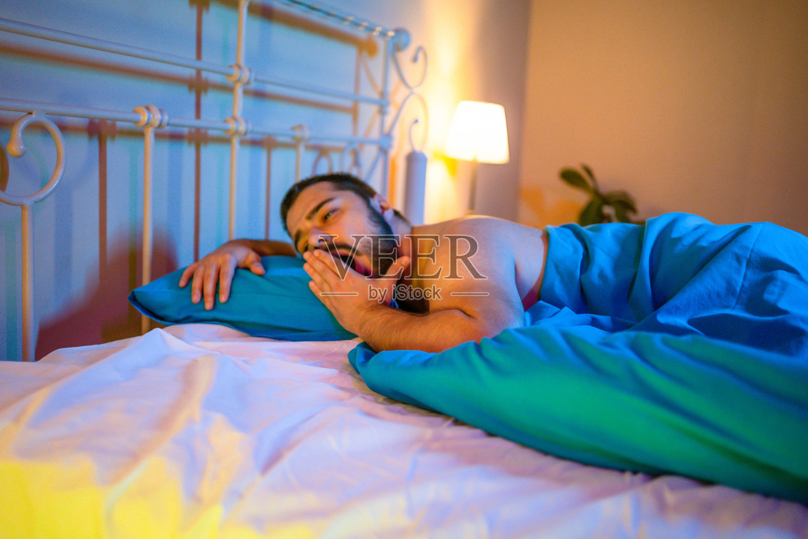 晚上有人在床上打哈欠照片摄影图片