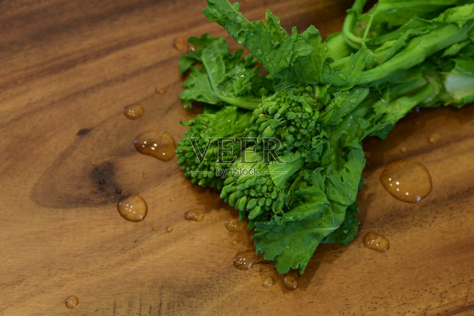 新鲜的油菜花在木砧板上。照片摄影图片