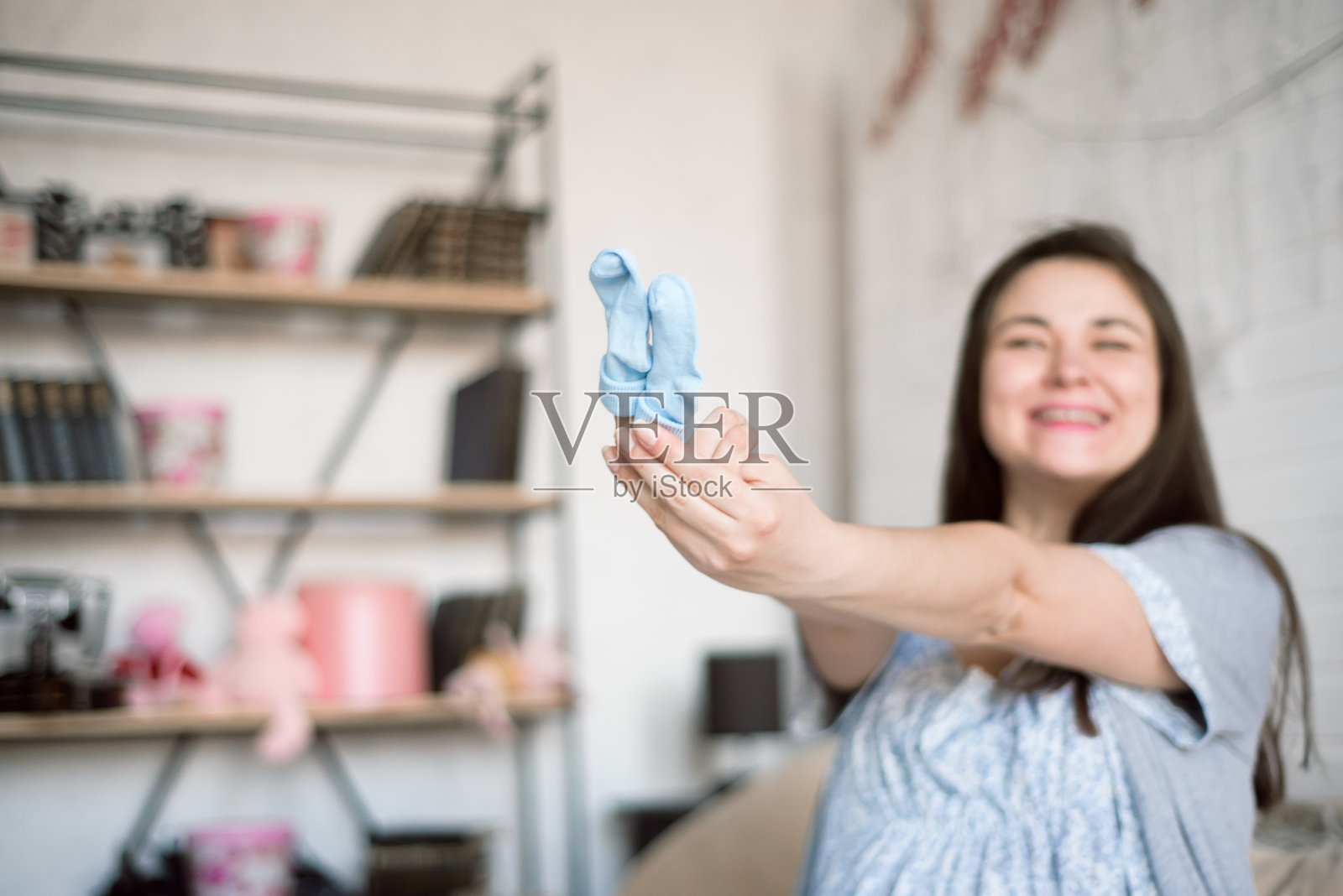 孕妇看婴儿衣服。年轻的母亲在等待一个婴儿。照片摄影图片