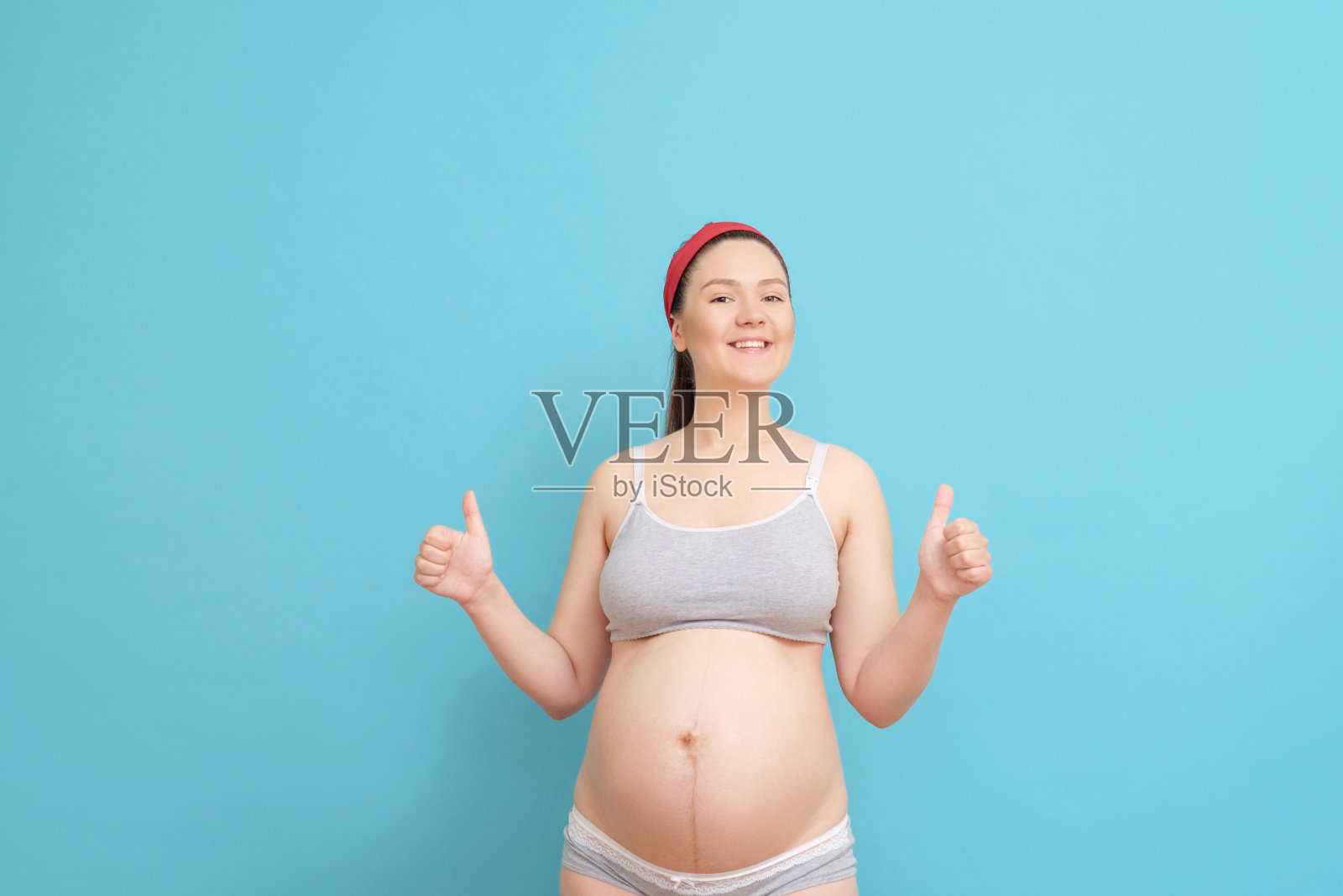 蓝色背景下的快乐年轻孕妇照片摄影图片