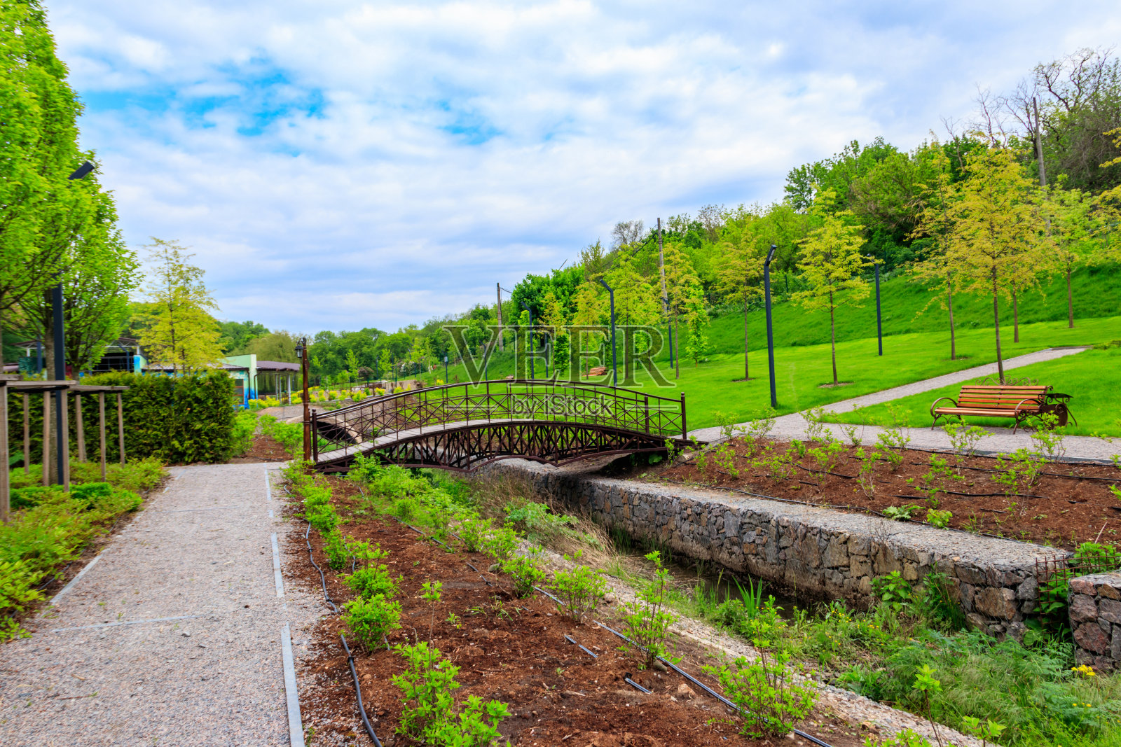 美丽的城市公园景观，拱形人行桥横跨小河和小树照片摄影图片