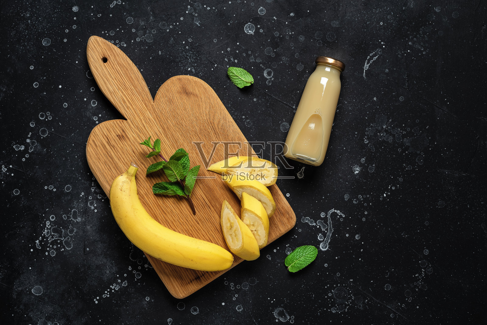 瓶子里的香蕉汁和黑色垃圾背景上的新鲜香蕉。俯视图，平放，复制空间。照片摄影图片