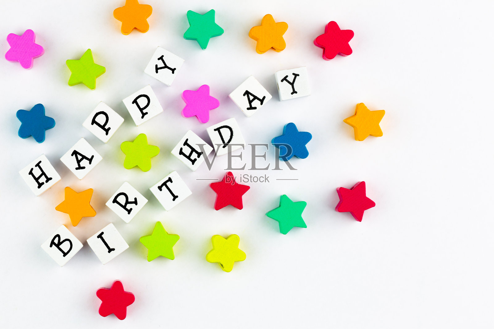 “生日快乐”的文字由积木排列在一个木制的背景上，旁边是五颜六色的星星照片摄影图片