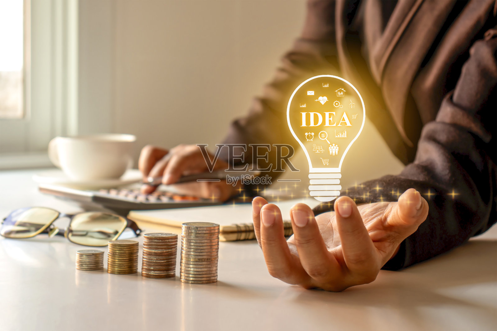 一个拿着灯泡的商人，桌上摆着他的想法，关于金融，投资和经营一个成功的企业的想法。照片摄影图片