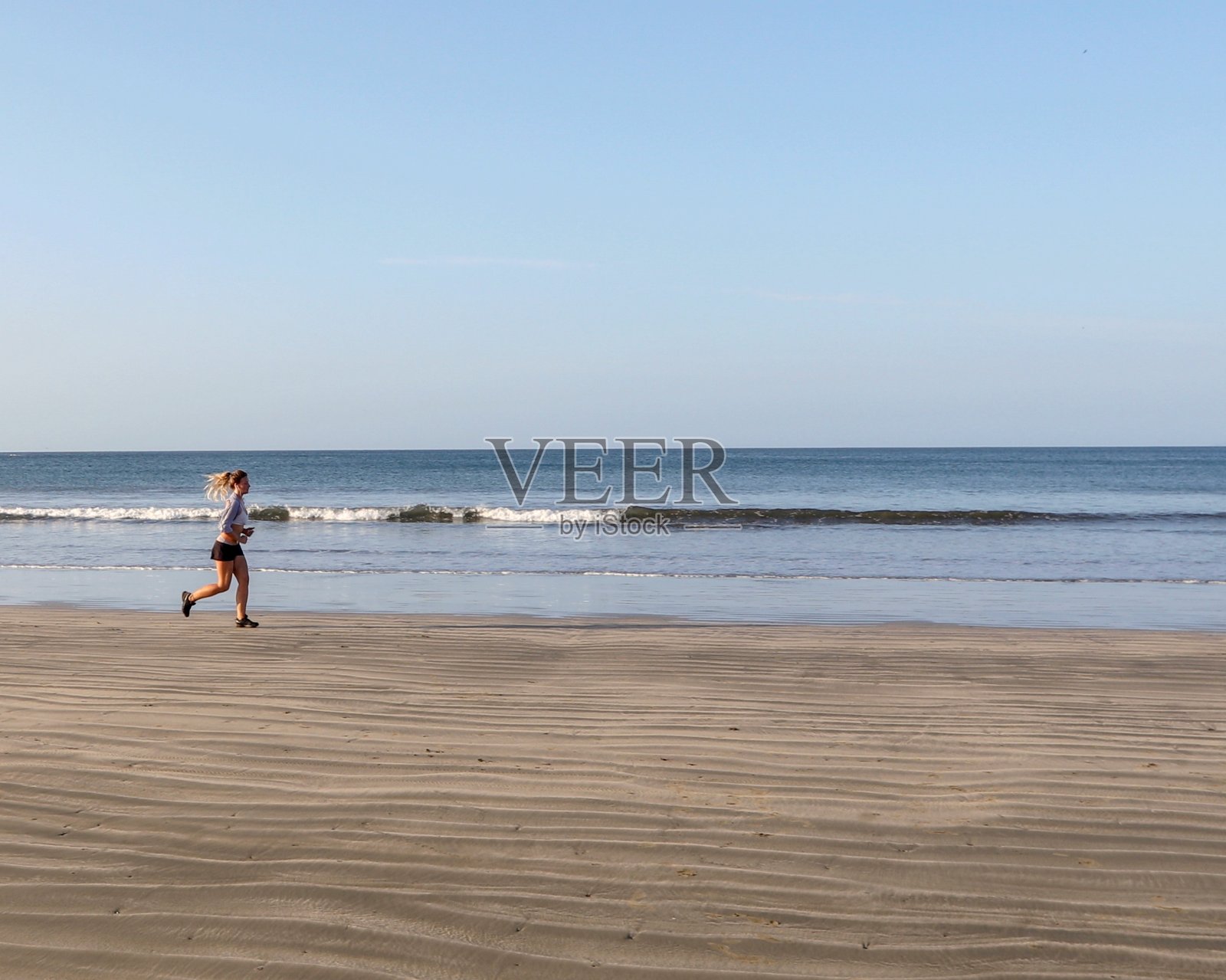 年轻的女人在早晨跑下沙滩照片摄影图片