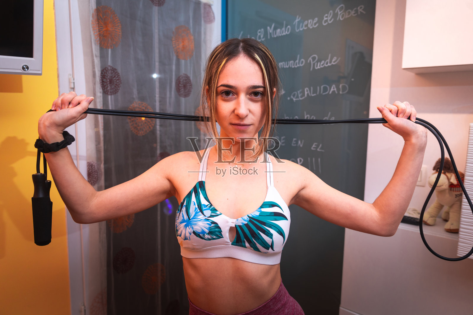 年轻的白人女孩摆姿势穿着运动服和橡皮筋在家。照片摄影图片