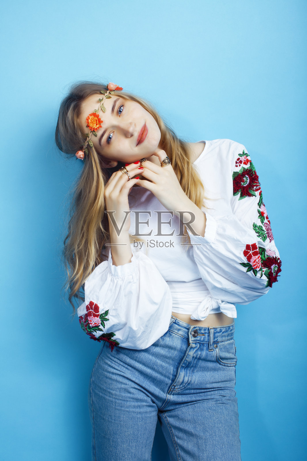 年轻漂亮的金发女孩摆姿势在蓝色背景，时尚风格的嬉皮波西米亚花在头部特写照片摄影图片