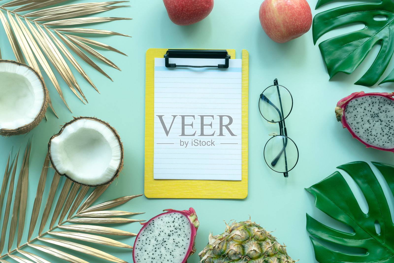 热带框架，背景与剪贴板，异国情调的水果和热带棕榈叶在绿色的背景。平躺照片摄影图片