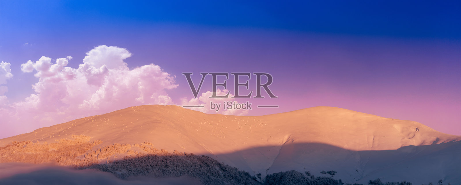 山的风景。积雪覆盖的山峰和黎明的雾。照片摄影图片