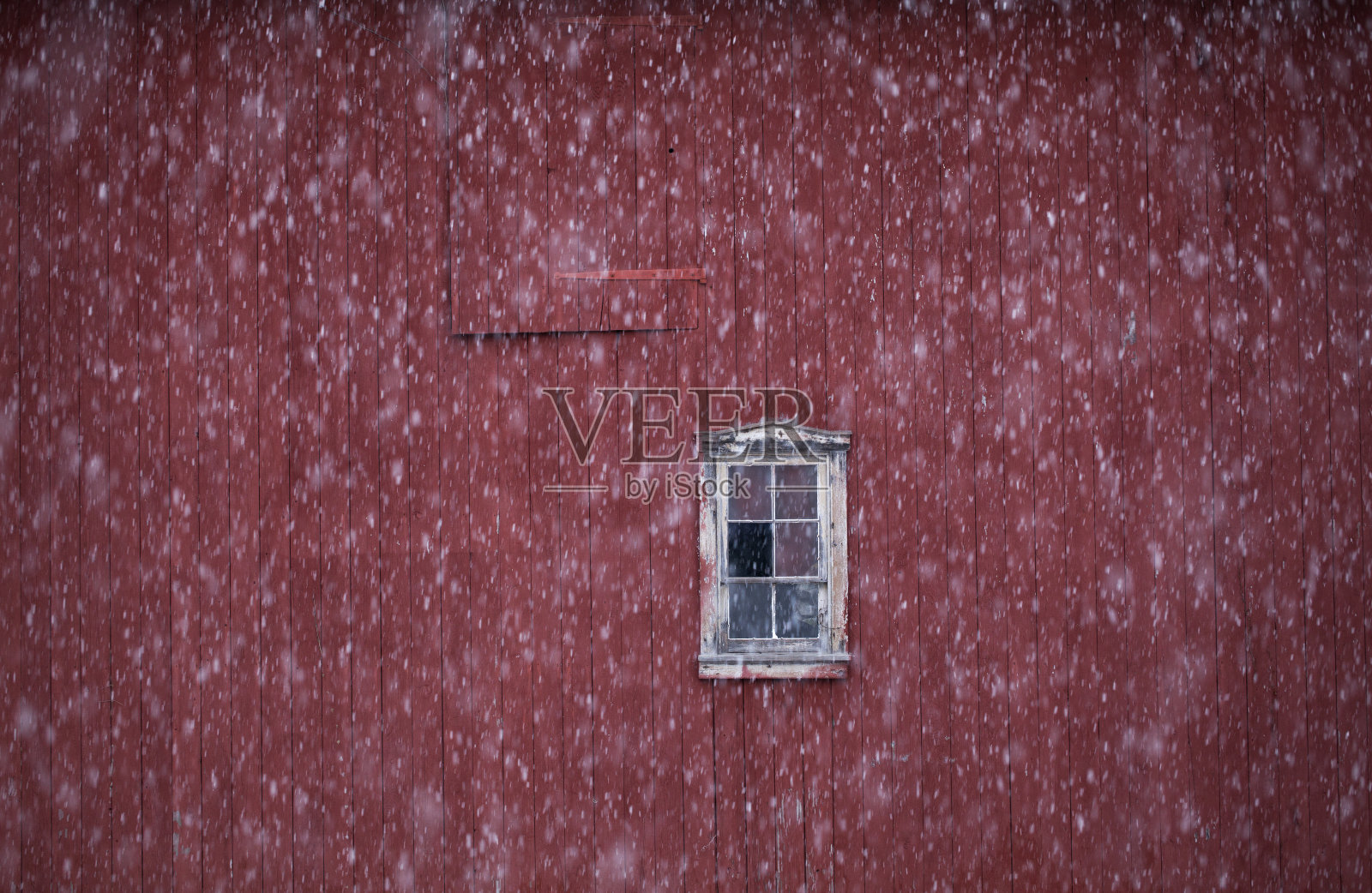 雪花映在有窗户的红色谷仓上照片摄影图片