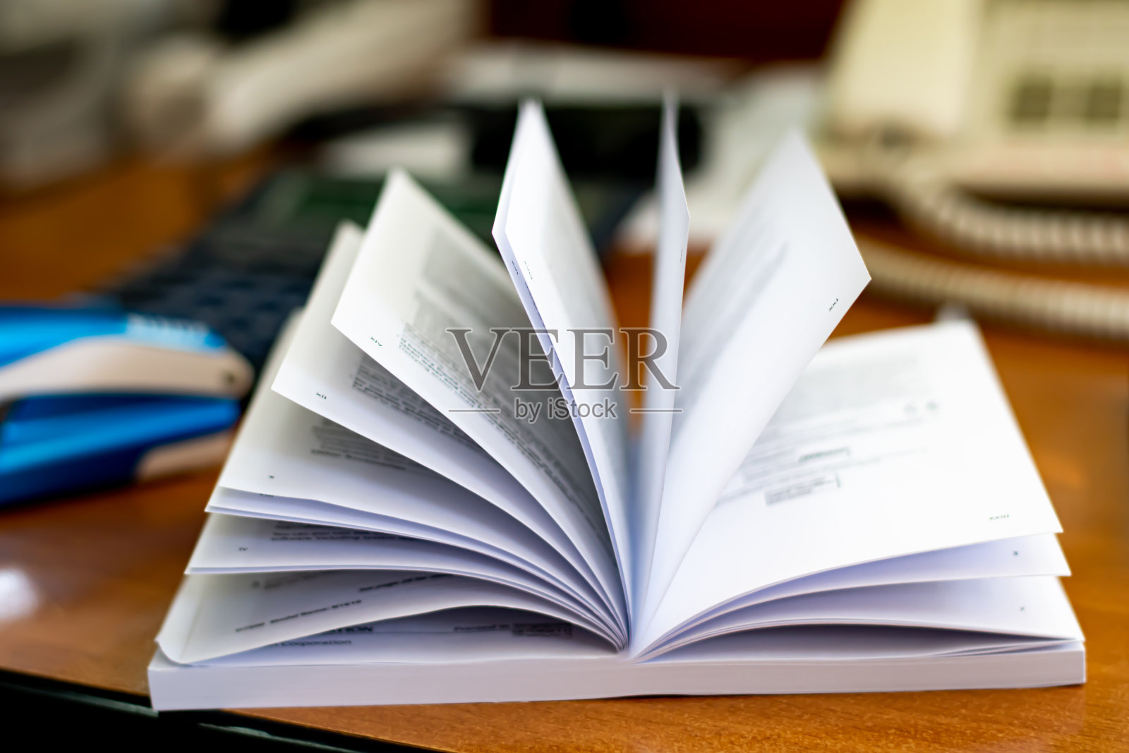 在办公室的桌子上，一页模糊的打开的书照片摄影图片