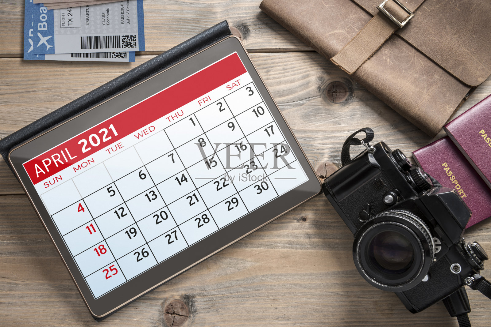 电子平板显示器、相机、护照、旅行登机牌放在桌上。照片摄影图片