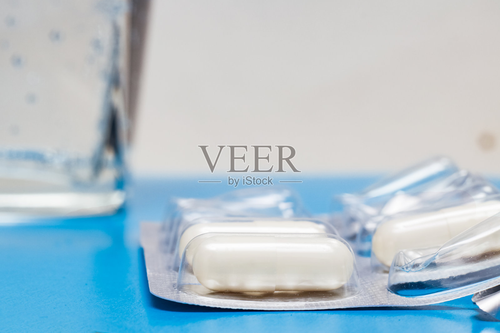 蓝色的桌子上放着药丸和一杯水照片摄影图片