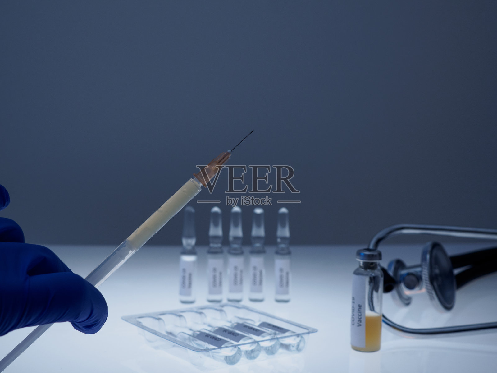 一位戴着蓝色手套的医生手中拿着一个装有covid-19疫苗的注射器。预防冠状病毒感染的疫苗接种照片摄影图片