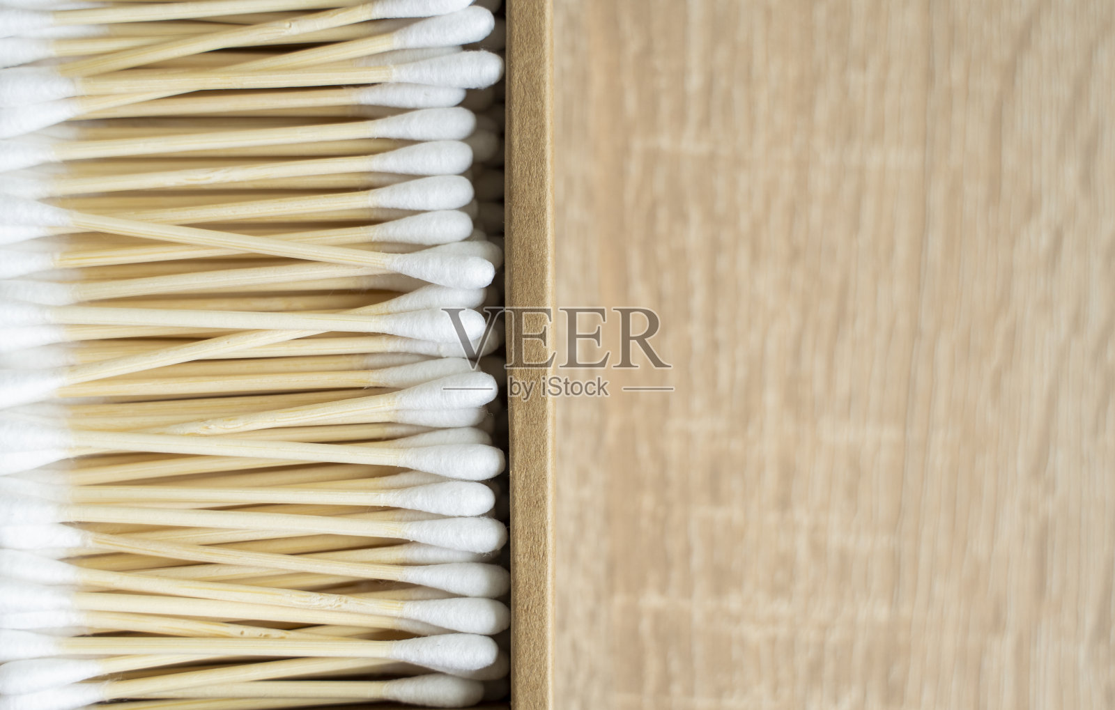 环保的棉签。桌子上放着一个装着可回收的竹棉花蕾的纸箱。“零浪费”的概念。生态产品。化妆棒放在盒子里。清洁耳朵的木棒。照片摄影图片