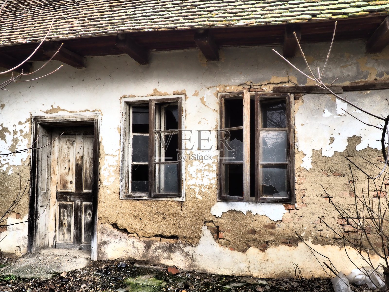 有窗户和门的旧房子。农村房子倒塌。城市化的概念和对祖国的遗忘。废弃的房子。窗户玻璃破碎，灰泥掉落。塞尔维亚。巴尔干半岛照片摄影图片