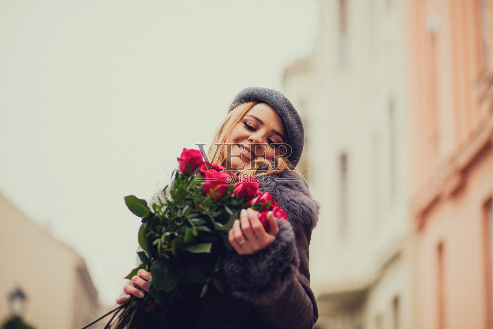 漂亮的年轻女子拿着一大束玫瑰走在街上照片摄影图片