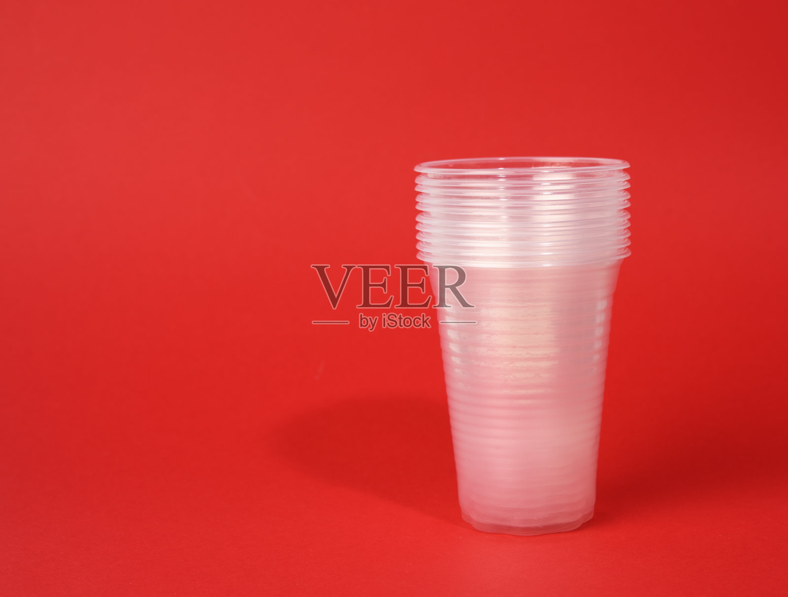 红色背景上的白色透明一次性杯子照片摄影图片