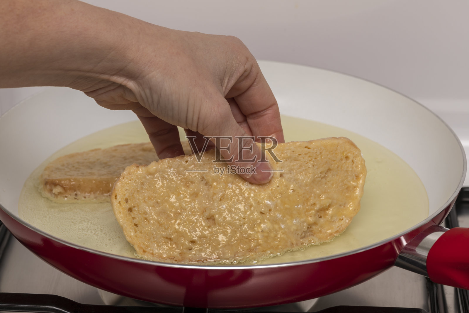 妇女的手和煎锅与油准备煎面包与鸡蛋和面粉(Torrijas)。典型的西班牙复活节糖果。传统的家庭烹饪理念。水平摄影和选择性对焦照片摄影图片