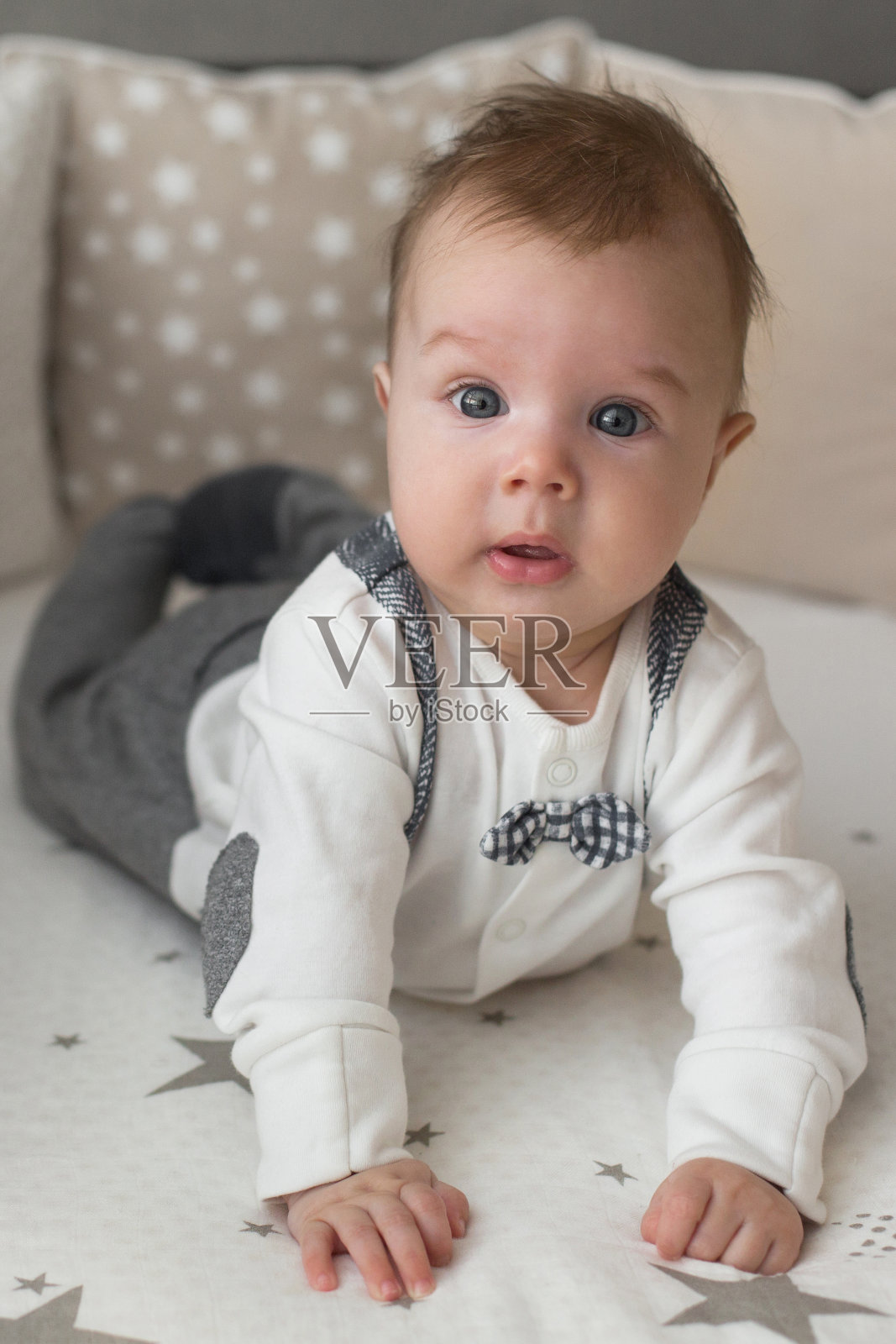 一个可爱的小男孩很惊讶地躺在床上。新生儿的特写肖像看着相机照片摄影图片