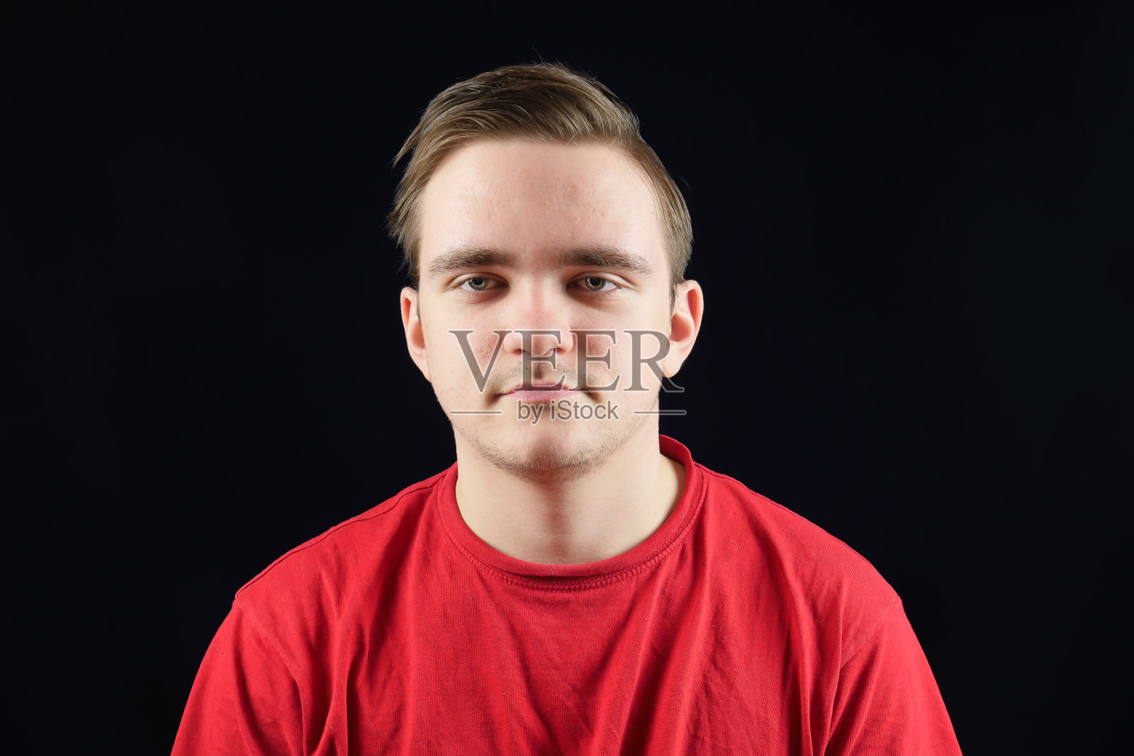 年轻英俊的男子在休闲t恤站在孤立的黑暗背景照片摄影图片