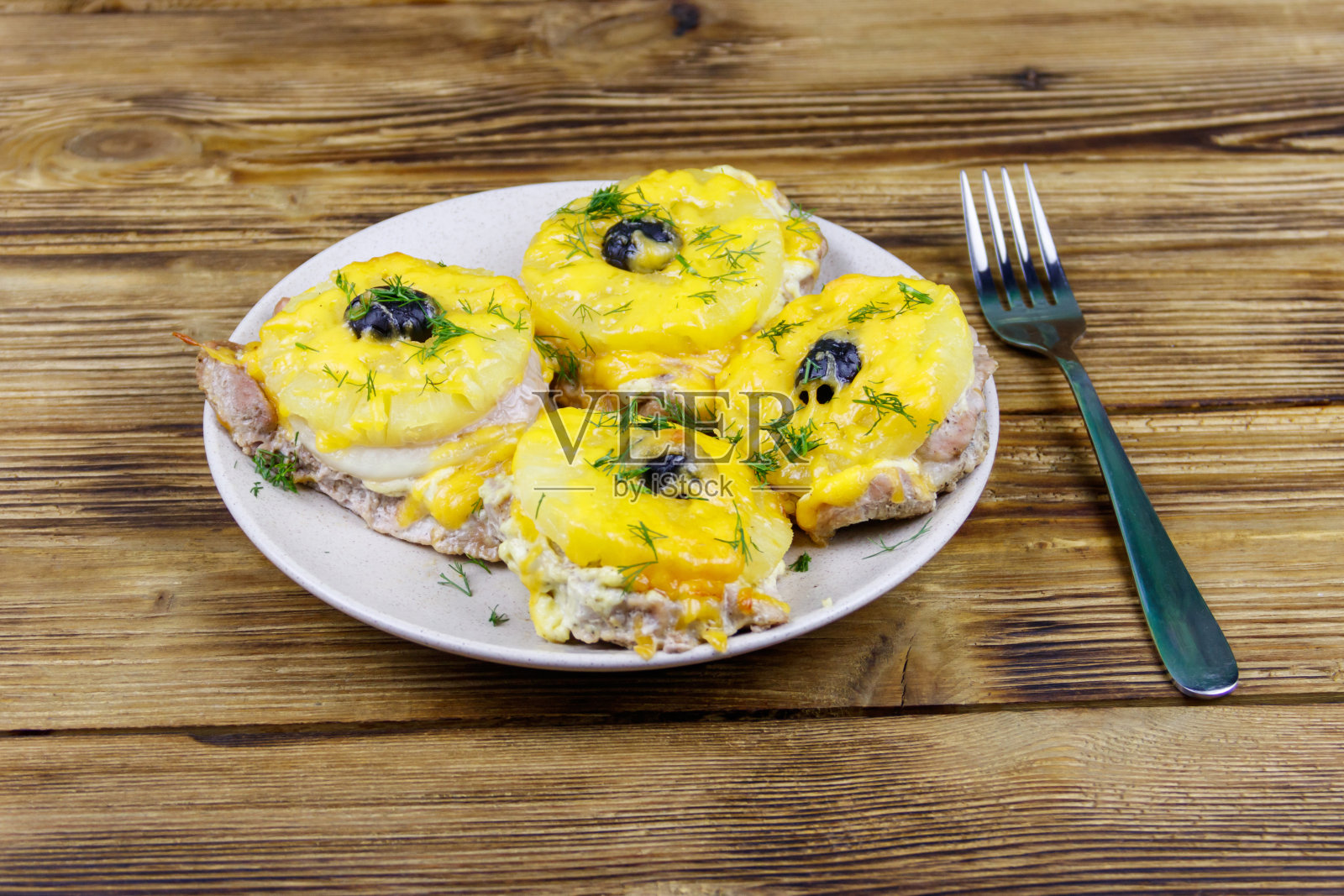 木桌上放着几块烤猪肉，配上菠萝、奶酪和橄榄照片摄影图片